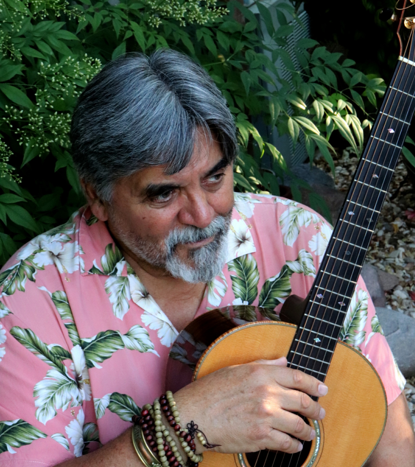 Mark with guitar and Hawaiian shirt looking away